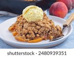 Peach Crisp or cobbler on plate with scoop of vanilla ice cream, horizontal