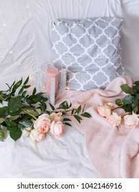 Peach flowers laying on white bed with grey pillow and pink knitted blanket. - Shutterstock ID 1042146916