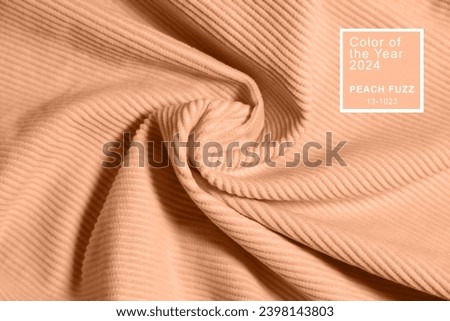 Peach fuzz, color of the year 2024, velvety fabric texture. Texture of velvet textile toned on peach fuzz color.