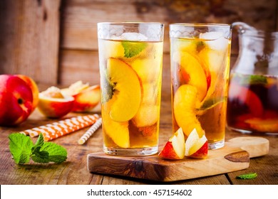 Peach ice tea in a glass with mint on wooden table
