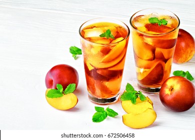 Peach ice tea in a glass with mint on a white wooden table(selective focus).