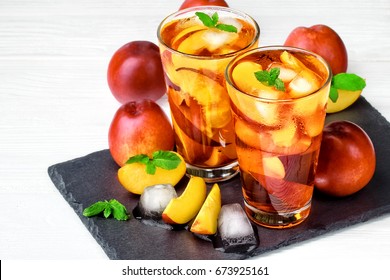 Peach ice tea in a glass with mint on a white wooden table(selective focus).