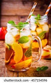 Peach ice tea in mason jar with mint on wooden table
