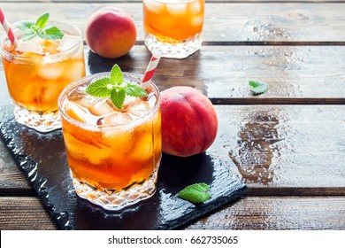 Peach iced tea. Iced tea with peach slices, mint and ice cubes close up. Homemade refreshing summer drink.
