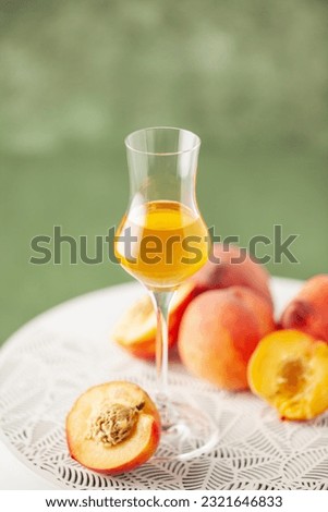 Peach liqueur in grappas glasses and fresh peaches on the table. Copy space