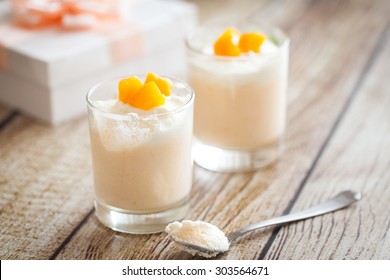 Peach souffle or mousse in glasses decorated with pieces of peach. Gift box on the background