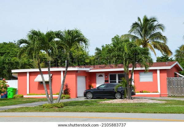 Peach Suburban Ranch style home with Royal Palm Trees
and Parked Car in USA