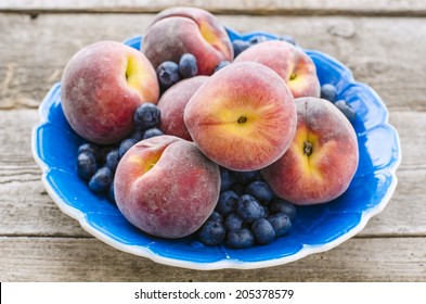 Peaches And Blueberries In The Blue Plate On The Wooden Table