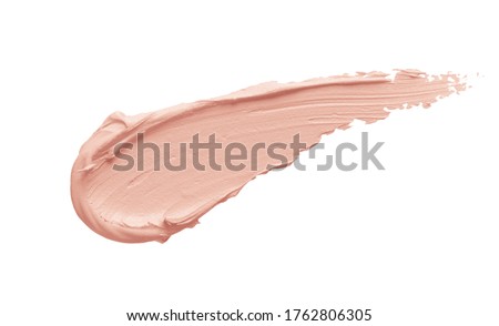 Peachy pink color correcting concealer smear smudge swatch isolated on white background. Thick cream texture. Skincare beauty product swipe closeup