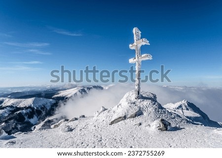 Peak cross on Dumbier hill in Low Tatras in Slovakia on chilly cold February day. Winter in Slovakian mountains with inversion in valleys and deep blue sky.  [[stock_photo]] © 