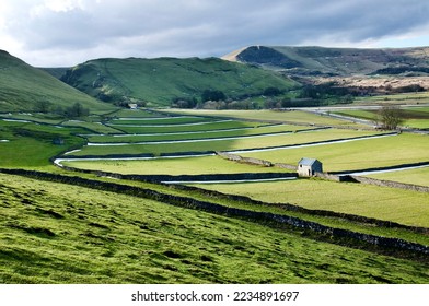Peak District landscape and agricultural land with background views of Mam Tor mountain range and disused buildings at Castleton.