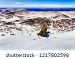 From the peak of Mt Back Perisher high in Snowy Mountains of Australia looking down to chairlift station for snowboarders and skiers above Perisher valley snow fields and ski resort slopes.