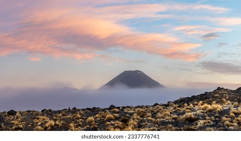 The peak of Ngauruhoe, also known as Mount Doom, emerging from the cloud during a cold sunrise. Tongariro National Park is a great place to visit some of New Zealand's volcanos. 