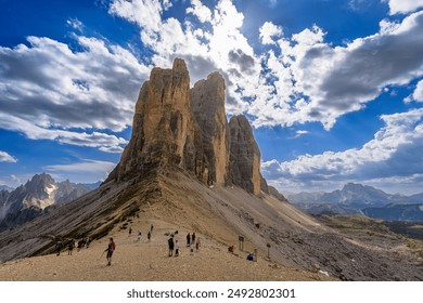 The peaks of Tre Cime di Lavaredo rise majestically in the sun, and their rugged faces light up against the sky, creating a stunning alpine landscape. - Powered by Shutterstock