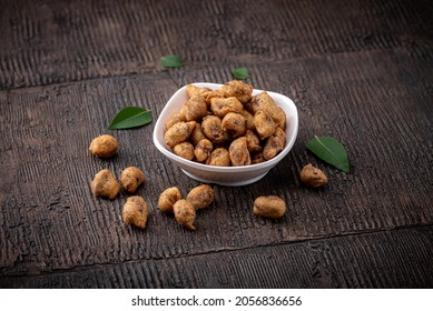 Peanut bhujia, Sing bhujia, is a very popular Gujarati Teatime Snack. Sing bhujia served in white bowl on wooden background with curry leaves.
Delicious Indian snack - Masala coated peanuts.