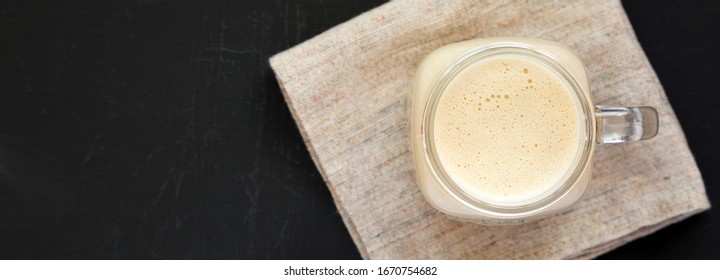 Peanut Butter Banana Smoothie In A Glass Jar On A Black Background, Top View. Flat Lay, From Above, Overhead. Copy Space.