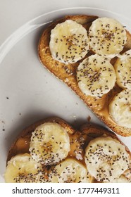 Peanut Butter Banana Toast On A White Plate, Chia Seeds On Top.