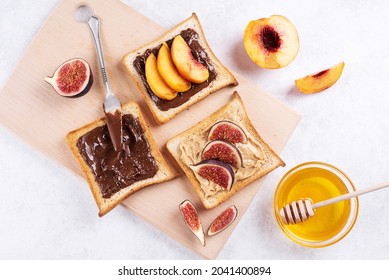 Peanut butter, chocolate spread with fruits on toast on a cutting board on a white background, healthy sweet breakfast, close-up. - Shutterstock ID 2041400894