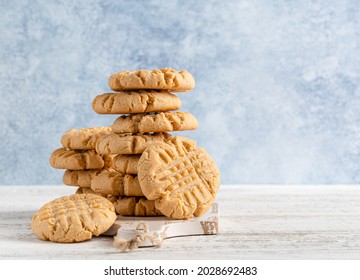 Peanut butter cookies stack on wooden cutting board. Traditional american dessert, nutrition snack, dessert or breakfast food. Blue and white background. Closeup food. Criss cross patterned biscuits. - Shutterstock ID 2028692483
