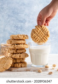 Peanut Butter Cookies Stacked On  White Cutting Board, Child Hand Soaking Biscuit In A Milk Glass. Blue And White Background. Closeup Food. Criss Cross Patterned Biscuits. American Breakfast.