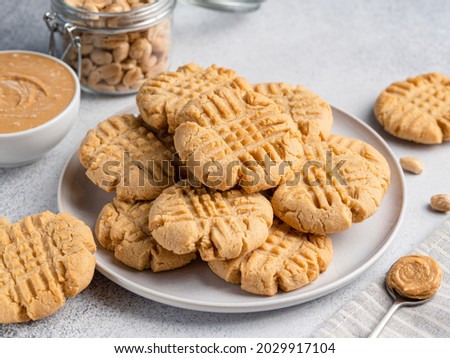 Peanut butter cookies stacked on ceramic plate. Close up view. Traditional american dessert, snack, dessert or breakfast food. Biscuits made of homemade nut butter, sugar, eggs and flour.