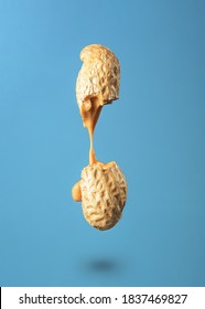 Peanut Butter Flows Out Of The Broken Peanuts On A Blue Background. 