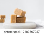 peanut butter fudge on a marble tray, soft peanut fudge squares  stacked on a white tray