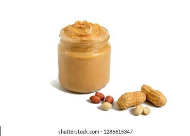Peanut butter in a glass jar with peanuts isolated on white background.  A traditional product of American cuisine.