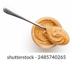 Peanut butter in glass jar and spoon isolated on white background, top view, copy space. American dessert concept