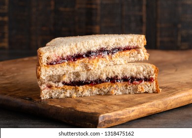 A Peanut Butter and Grape Jelly Sandwich on a Wooden Cutting Board