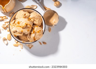 Peanut butter ice cream balls. A lot nuts gelato scoops in ceramic bowl, with caramel sauce, white kitchen background copy space - Powered by Shutterstock