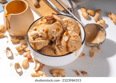 Peanut butter ice cream balls. A lot nuts gelato scoops in ceramic bowl, with caramel sauce, white kitchen background copy space - Powered by Shutterstock