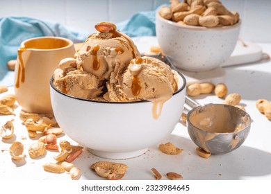 Peanut butter ice cream balls. A lot nuts gelato scoops in ceramic bowl, with caramel sauce, white kitchen background copy space - Powered by Shutterstock