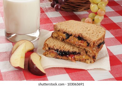 A Peanut Butter And Jelly Sandwich With Apple Slices And Milk