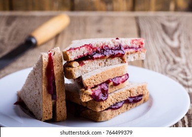 Peanut butter and jelly sandwich with whole wheat bread on rustic wooden table  
