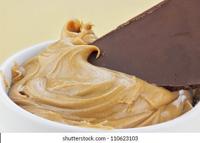 Peanut Butter With A Piece Of A Chocolate Candy Bar Dipped Into It.