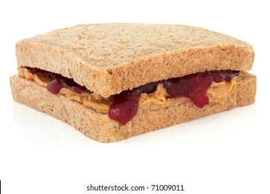 Peanut butter and raspberry jam sandwich on brown bread, over white background.