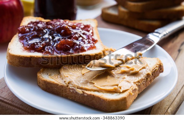 Peanut butter and raspberry\
jelly sandwich on wooden background. Perfect sweet breakfast. Close\
up.