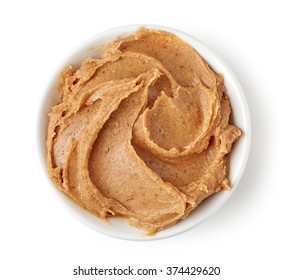 Peanut butter in round dish isolated on white background, top view