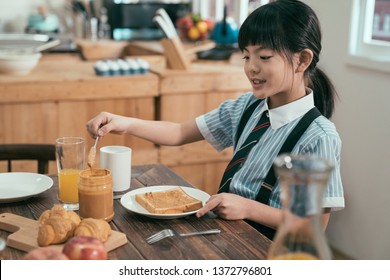 Peanut Butter Sandwich Toast Bread On Wooden Table Kitchen At Home Morning. Smiling Happy Little Kid Elementary School Student In Uniform Before Study Eating Breakfast. Cute Child Having Healthy Meal