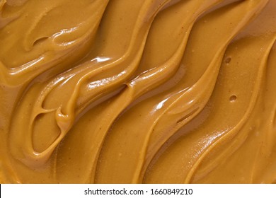 Peanut butter texture background. Creamy smooth brown nut spread smear closeup. Delicious dark natural food paste macro top view