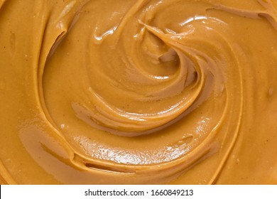 Peanut Butter Texture Background. Creamy Smooth Brown Nut Spread Swirl Close Up. Delicious Dark Natural Food Paste Macro Top View