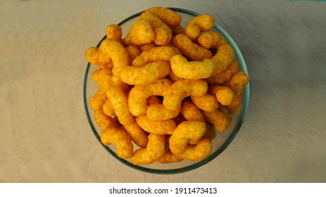 peanut flips . lots of corn sticks in peanut glaze in a glass round bowl in the middle on a gray light background top view