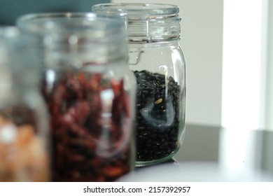 Peanuts, chili, black beans. Nuts in glass jars with lid in kitchen counter. Raw materials for cooking. Food ingredient image for background, book, website, cover page. Glass bottle flavoring