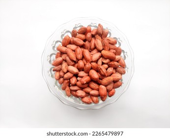 Peanuts or groundnuts in a glass bowl isolated over white background. Bunch of unpeeled red groundnuts without shell.Peanuts are also know as earthnut, goober or monkey nut.