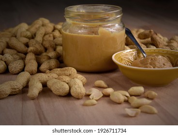 Peanuts and peanut butter in a jar on the table close-up stock images. Pile of peanuts and a glass of peanut butter on a wooden background detail stock photo