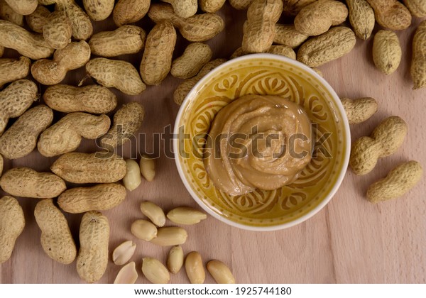 Peanuts and peanut butter in a\
jar on the table top view stock images. Pile of peanuts and bowl of\
peanut butter stock photo. Peanuts on a wooden background top\
view