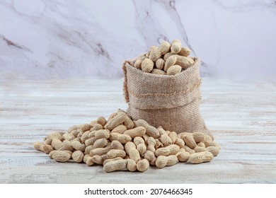 Peanuts with shell. Also groundnut or goober. Pile of unshelled, dry roasted whole pods of Arachis hypogaea, used as snack, oil crop and grain legume. Macro food photo close up from above.