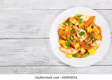 Pear, Kiwi Fruit, Apricot,mango And Peach Salad On White Dish Sprinkled With  Muesli On Wooden Kitchen Table, View From Above