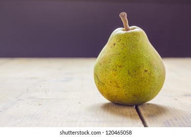 A pear on the table in front of a window